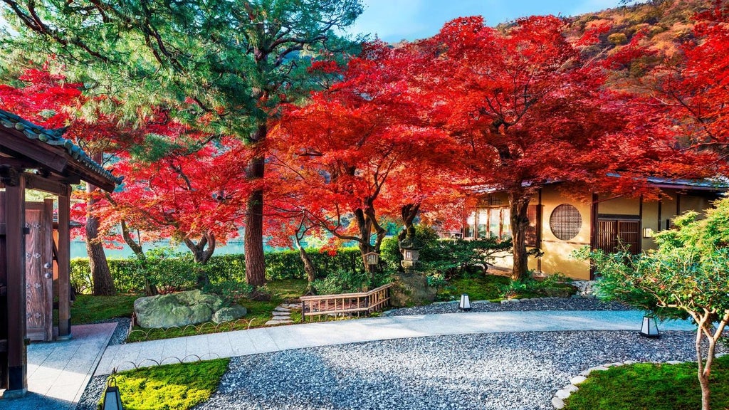 Elegant traditional Japanese ryokan-style luxury hotel nestled by Arashiyama's lush gardens, featuring wooden architecture and serene water elements in Kyoto