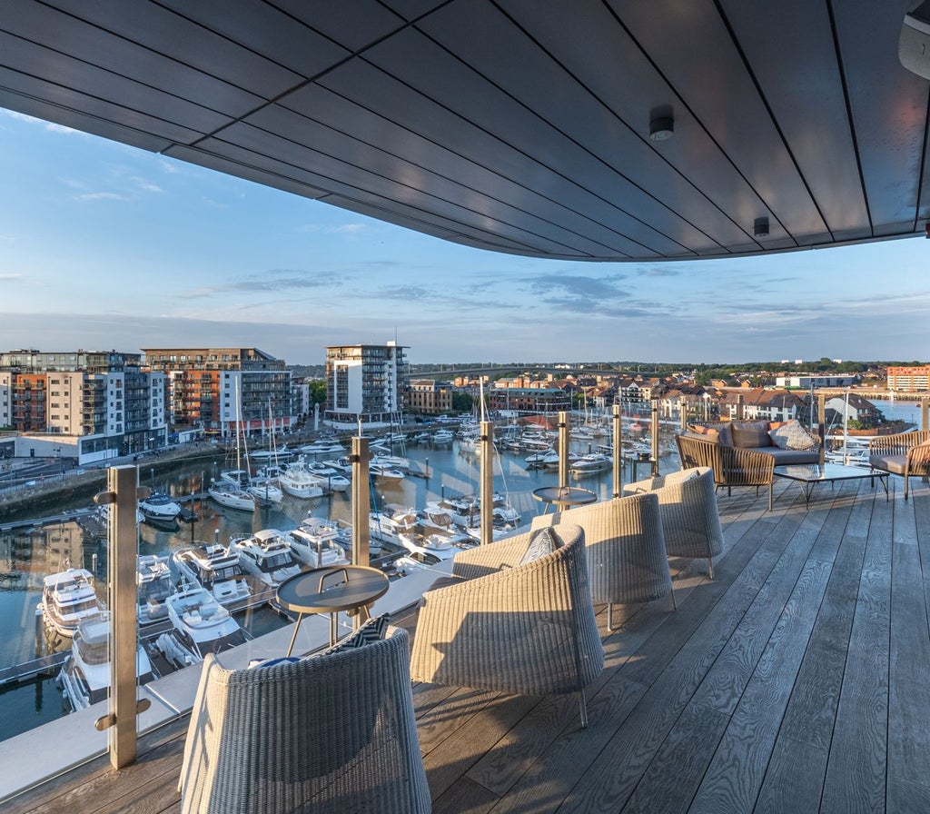 Luxurious waterfront hotel with modern architecture, overlooking Southampton harbor, featuring sleek design and elegant glass facade at dusk