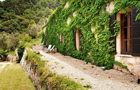 Elegant stone villa nestled in lush Mallorcan landscape, featuring terracotta roofs, arched windows, and panoramic views of scenic Valldemossa countryside