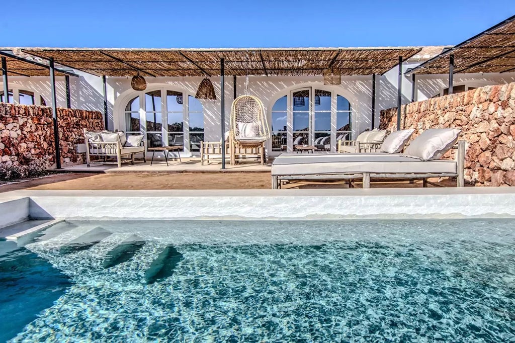 Luxurious pool suite with modern Mediterranean design, featuring sleek white decor, panoramic windows, and an inviting infinity pool overlooking scenic landscape