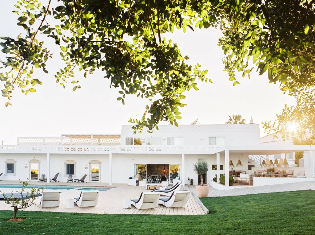 Rustic stone hotel with wooden terrace overlooking lush green Portuguese countryside, showcasing traditional architecture and serene rural charm