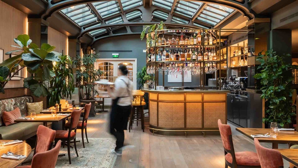 Elegant Parisian hotel facade with warm stone exterior, wrought-iron balconies, and soft evening lighting, showcasing chic boutique design in the Marais district.