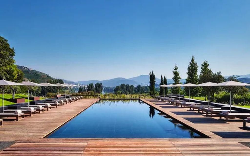 Modern luxury resort nestled in terraced vineyards overlooking Douro Valley, featuring infinity pool and contemporary architecture