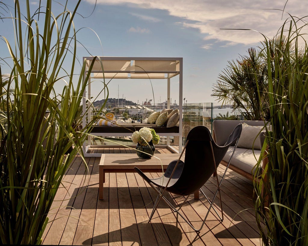 Luxurious penthouse suite with panoramic windows, modern minimalist design, white and wood accents, overlooking scenic coastal landscape at Sir Joan Hotel in Spain