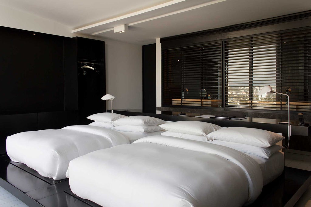 Modern deluxe twin hotel room with sleek design, city view, minimalist furniture, and warm neutral color palette in Monterrey, Mexico.