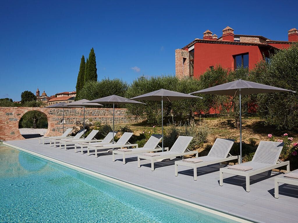 Rustic stone facade of elegant Scenset Hotel 69, nestled in Tuscan countryside with cypress trees and golden sunset lighting