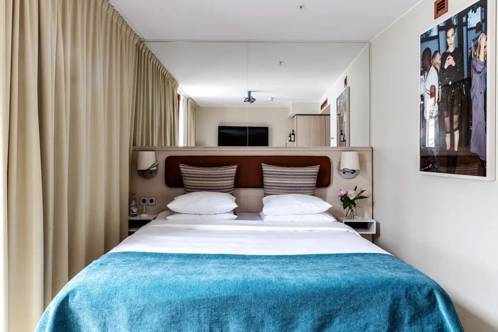 Elegant contemporary hotel room with plush white bedding, minimalist Nordic design, dark wood accents, and soft ambient lighting at luxury Scenset hotel