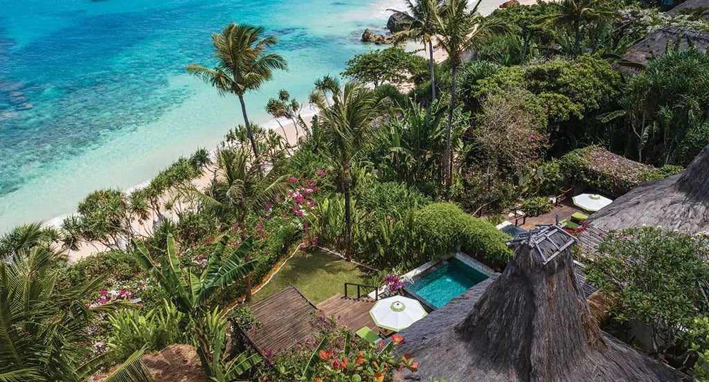 Luxurious open-air Indonesian villa at NIHI Sumba, featuring expansive wooden deck, infinity pool overlooking lush tropical landscape and ocean horizon