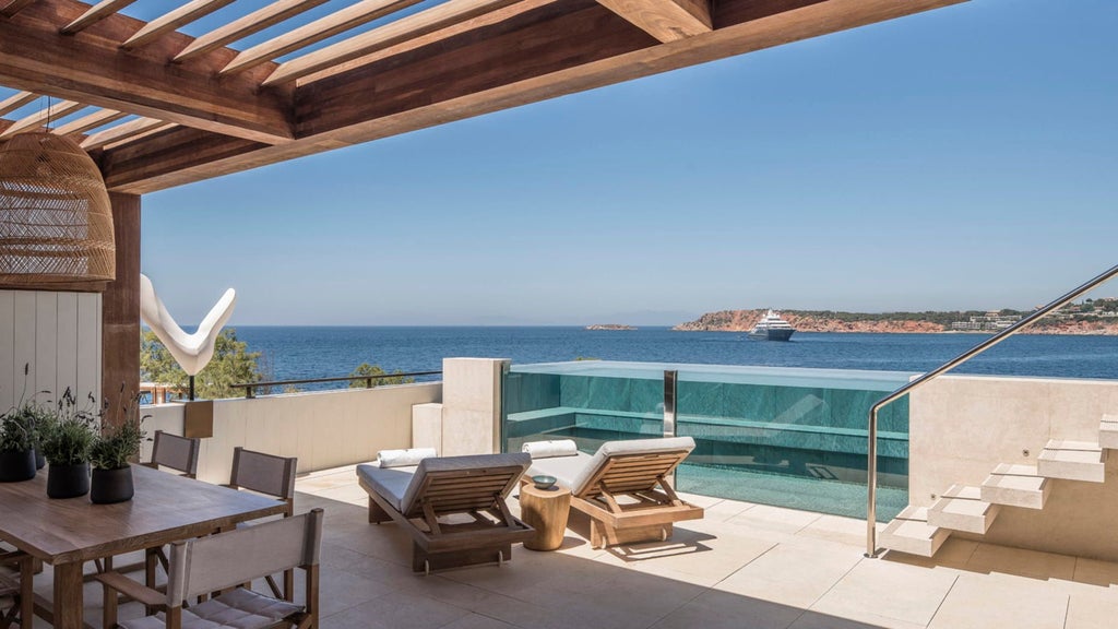 Luxurious terrace suite overlooking Aegean Sea, featuring private infinity pool, modern loungers and elegant outdoor dining setup