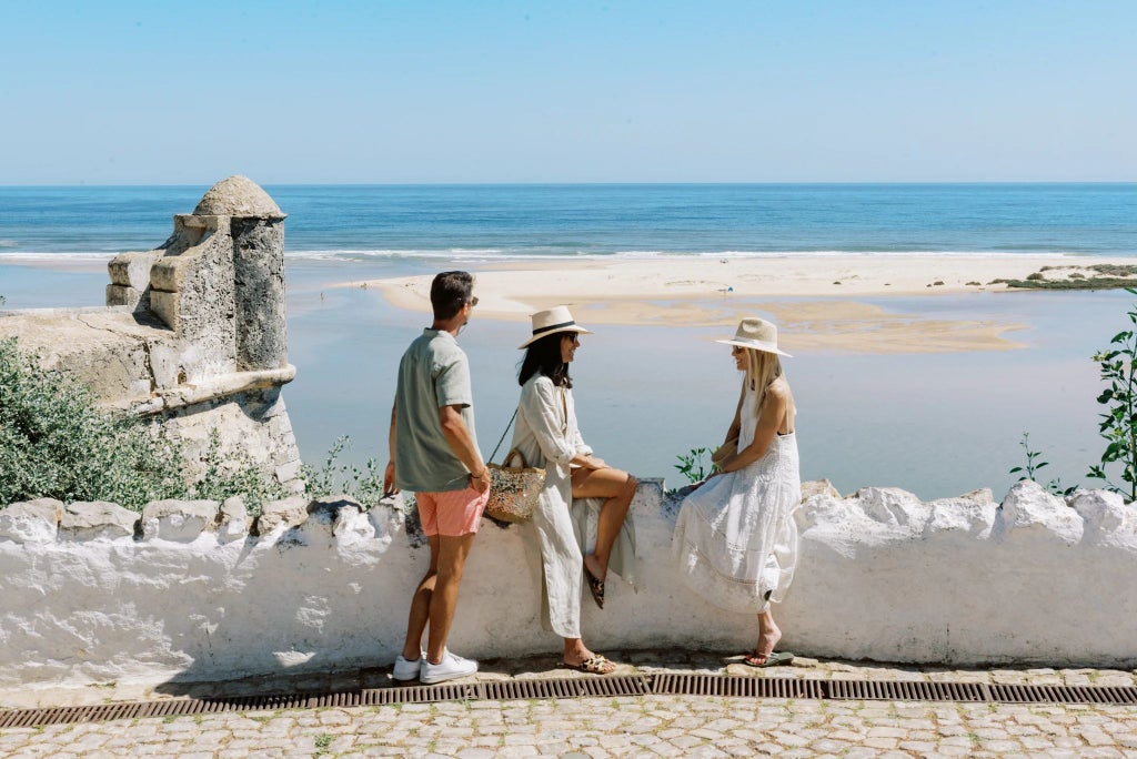 Rustic stone villa with wooden terrace overlooking lush Portuguese countryside, warm sunset light casting golden hues on traditional architectural details