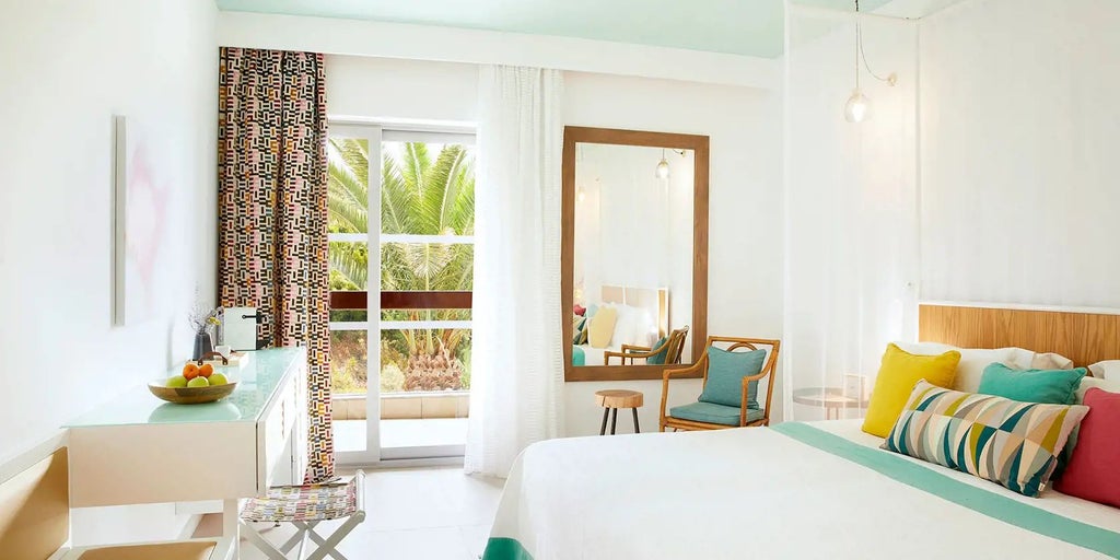 Elegant double room with garden view at Eagles Palace, featuring plush white bedding, minimalist decor, and serene Grecian landscape through large windows