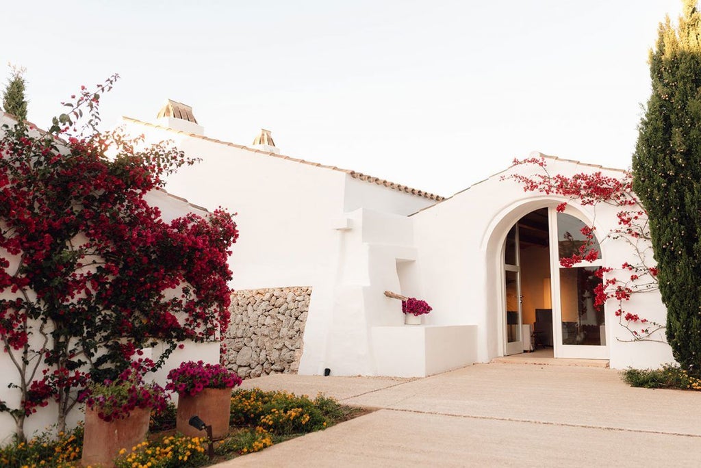 Luxurious white-washed Spanish farmhouse hotel nestled in scenic Menorcan countryside with stone walls and rustic Mediterranean charm