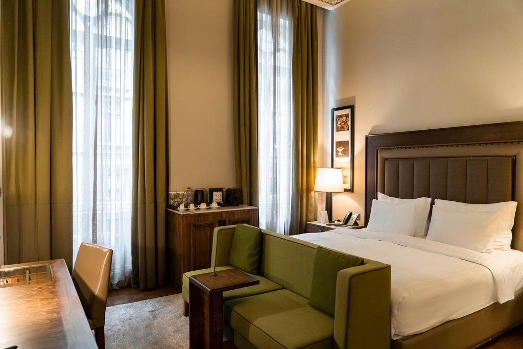 Luxurious deluxe king room at the Bank Hotel Istanbul, featuring elegant design, plush bedding, and sophisticated decor with city views through large windows.