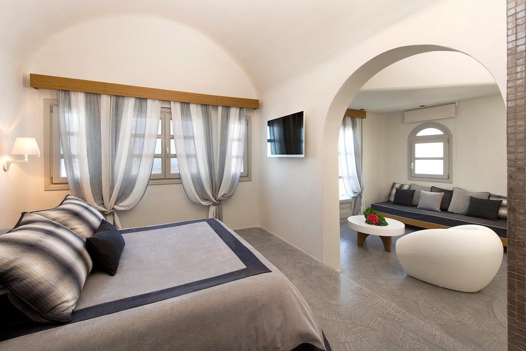 Luxurious Avaton Suite overlooking the Aegean Sea, featuring elegant white-draped bed, minimalist design, and panoramic blue ocean view in Santorini, Greece