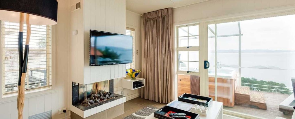 Luxurious lakeside hotel room with wooden furnishings, panoramic lake view, and modern amenities at scenset Lake Cottages in scenic New Zealand landscape