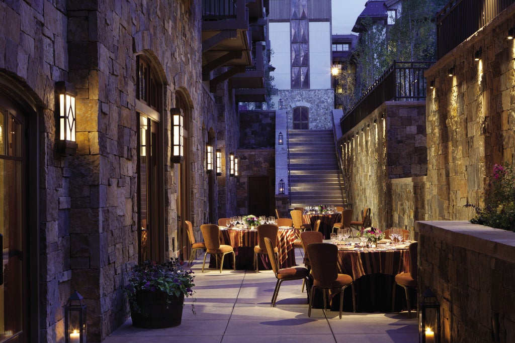 Elegant stone and timber Four Seasons Vail resort nestled against snow-capped mountains, featuring grand archways and luxury balconies