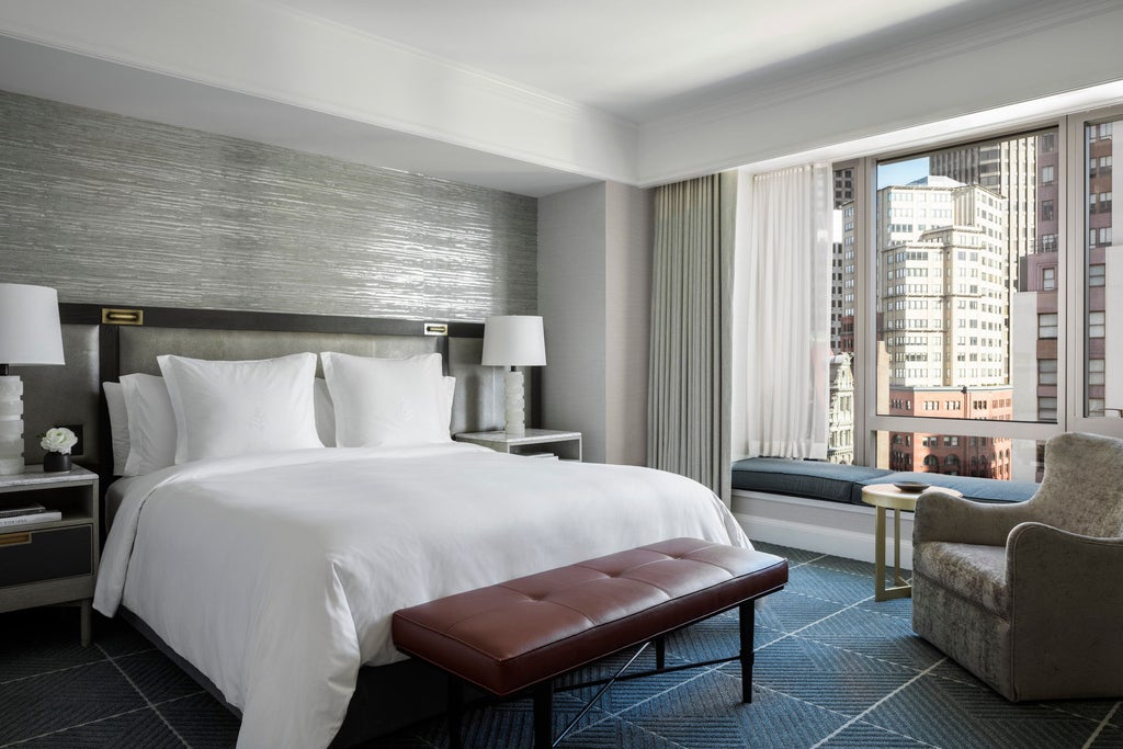 Modern luxury hotel tower with floor-to-ceiling windows, rising above San Francisco's Financial District with city skyline views