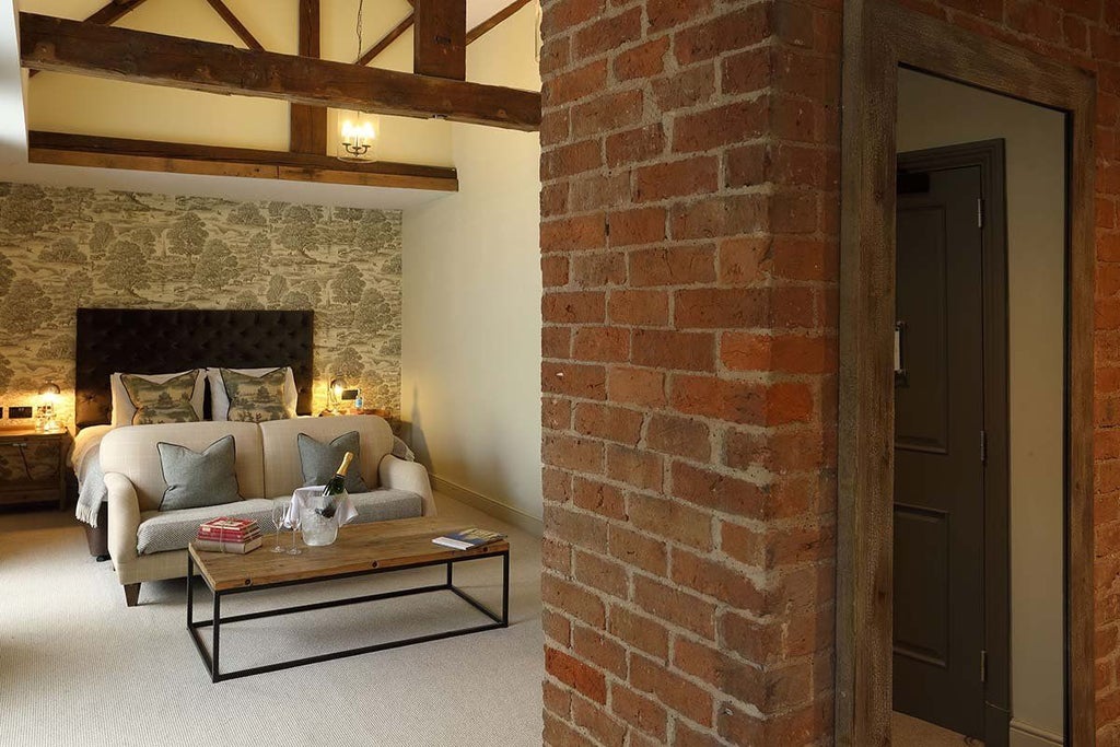 Elegant feature room at Kings Head Hotel with plush king bed, rich wooden furnishings, soft neutral tones, and sophisticated British countryside decor