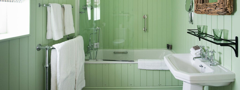 Luxurious coastal hotel room with crisp white linens, soft neutral tones, elegant wooden furniture, and panoramic sea view in Southwold, UK.