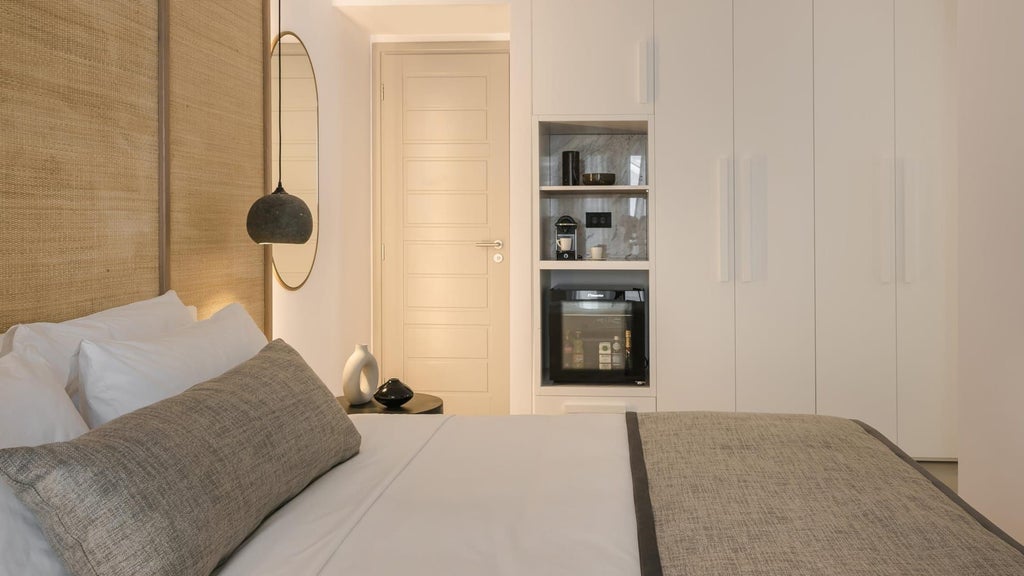 Elegant two-bedroom deluxe room with white minimalist decor, Aegean Sea view, contemporary Greek design, and luxury sea-facing balcony in Mykonos.