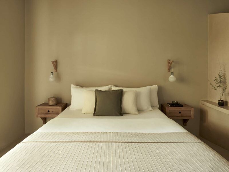 Elegant Greek hotel room with minimalist design, soft white linens, wooden furniture, and lush garden view through large windows at F Zeen Kefalonia resort