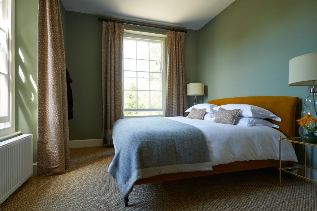 Elegant boutique hotel room with soft neutral color palette, plush white bedding, minimalist decor, and warm ambient lighting in a historic UK setting