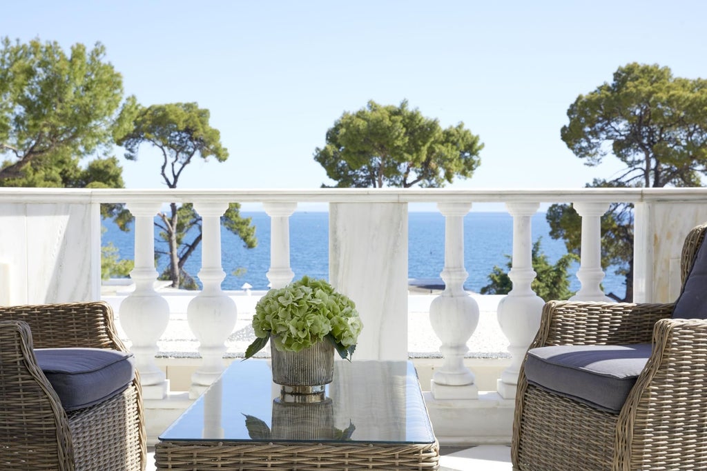 Spacious luxury suite at scenset Beach Resort with panoramic Aegean Sea view, private balcony, elegant white decor, and sweeping coastal landscape beyond