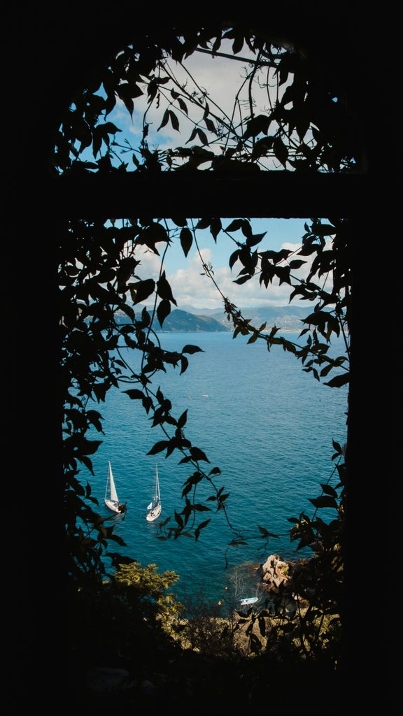 Wooden Riva boat gliding through crystal-clear Mediterranean waters along Portofino's colorful waterfront villas and luxury yachts