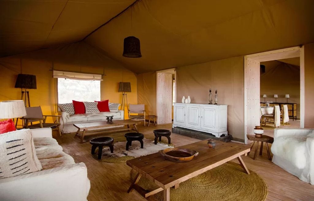 Luxury canvas safari tent perched on Ngorongoro Crater rim with panoramic savanna views and elegant outdoor wooden deck furnishings