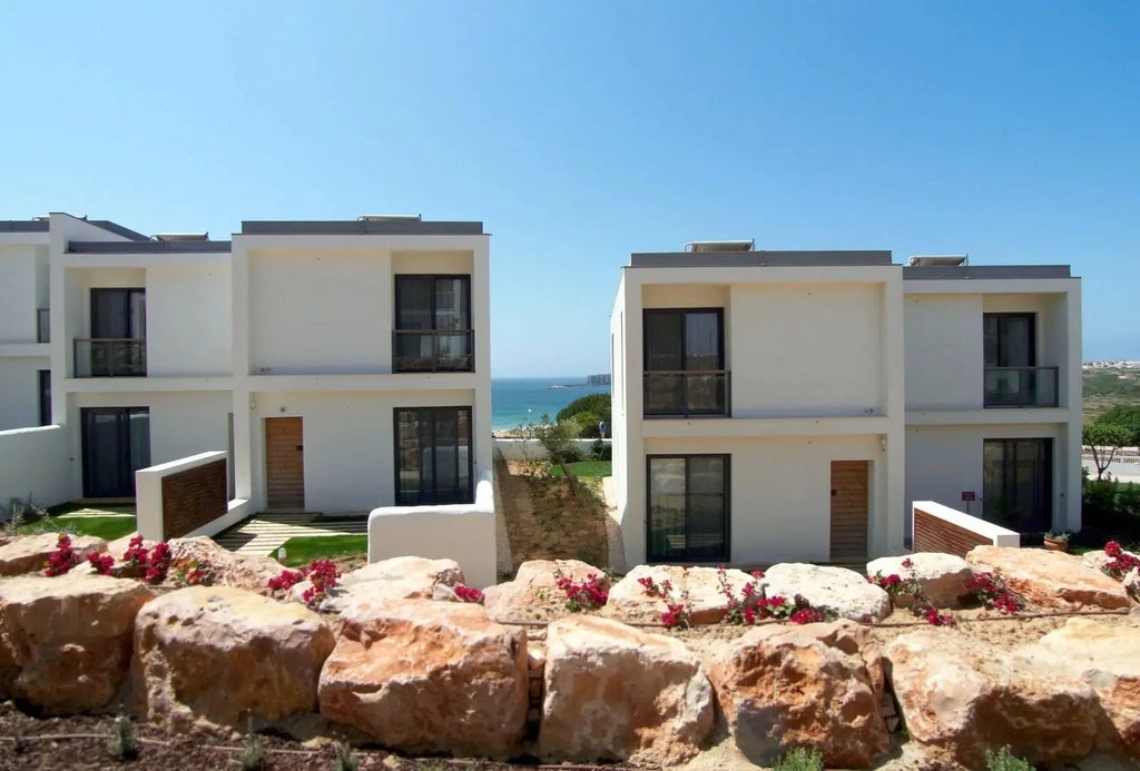 Luxurious ocean-view suite at Martinhal Sagres Resort, featuring modern design, floor-to-ceiling windows, and panoramic coastal landscape of Portugal's Algarve.