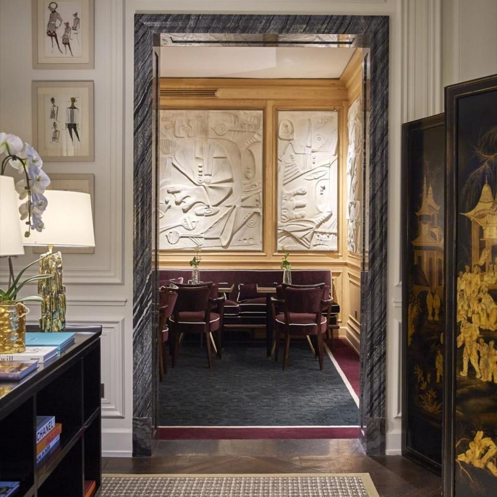 Elegant Parisian luxury hotel interior with plush velvet seating, marble fireplace, and sophisticated neutral color palette reflecting French design excellence