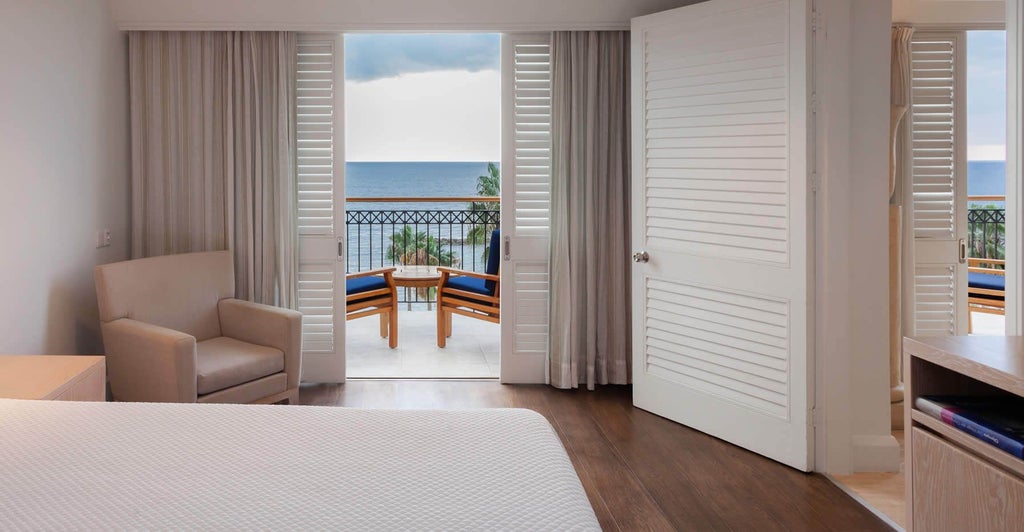 Spacious two-bedroom deluxe suite at scenset hotel in Cyprus, featuring elegant modern decor, plush beds, panoramic coastal view, and luxurious marble bathroom