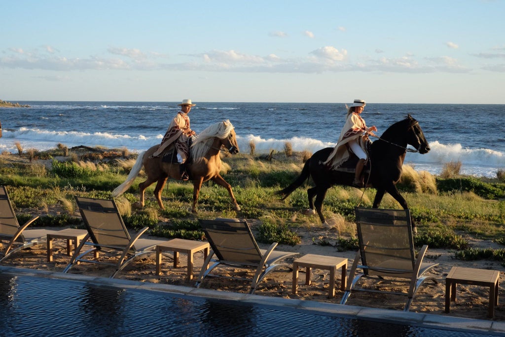 Luxurious beachfront hotel with minimalist design, nestled on sandy coastline, featuring modern architecture and natural landscape of Uruguay's José Ignacio region