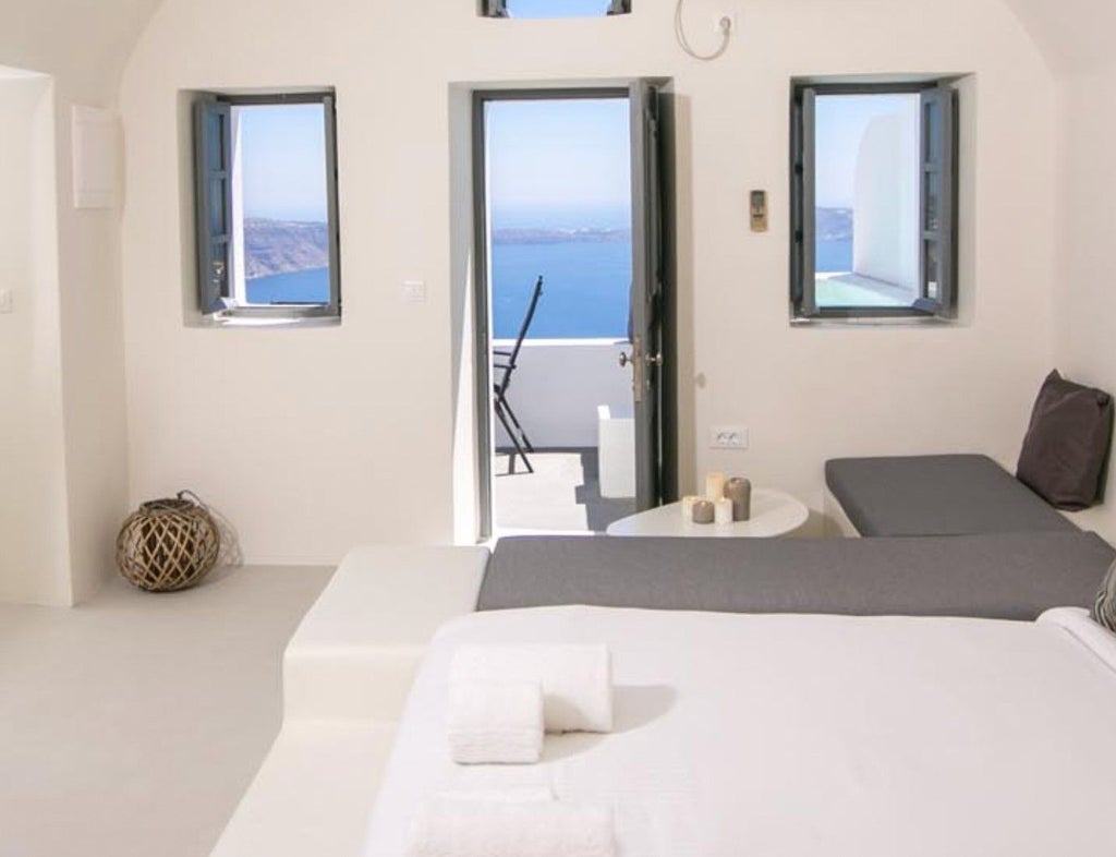 Pristine white luxury hotel building with private balconies overlooking crystal-clear Mediterranean waters in Santorini, Greece