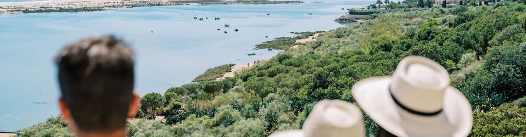 Charming traditional Portuguese hotel with rustic wooden veranda, whitewashed walls, terracotta roof, nestled among lush green landscape near scenic coastal region