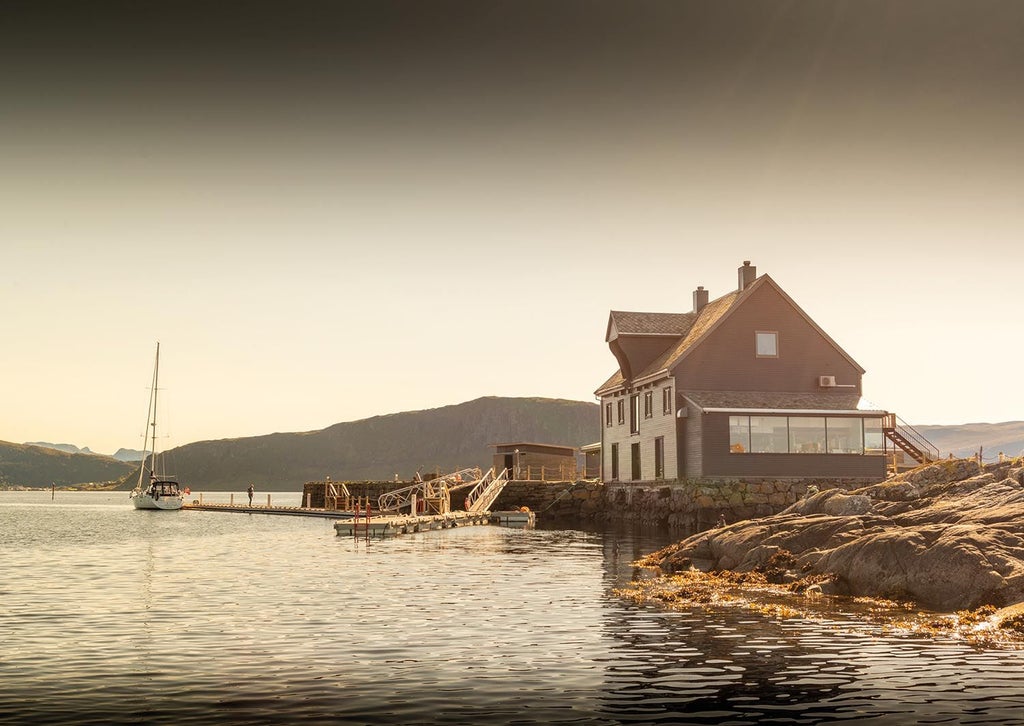 Luxurious private lunch on a serene Norwegian islet, with elegant table setting, gourmet cuisine, and breathtaking coastal landscape in the background