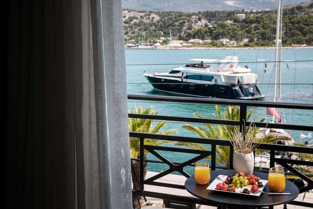 Elegant grand suite overlooking azure Aegean Sea, featuring plush white bedding, modern minimalist decor, and expansive floor-to-ceiling windows in Kefalonia, Greece