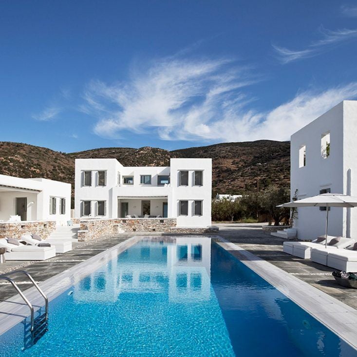 Luxurious whitewashed Cycladic hotel terrace overlooking azure Aegean Sea, with minimalist design and elegant infinity pool at sunset