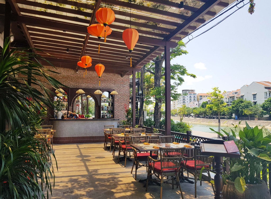 Luxurious Vietnamese boutique hotel lobby with warm wood tones, elegant traditional decor, and soft ambient lighting, showcasing refined architectural design