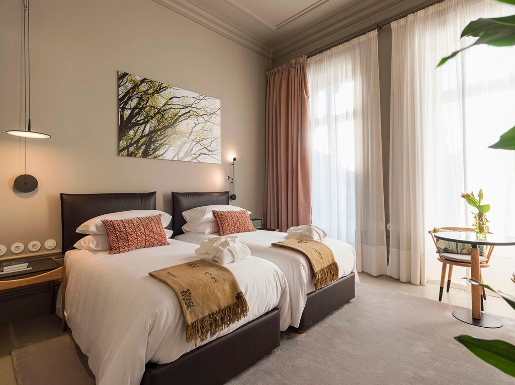 Elegant boutique hotel room with ornate wooden headboard, crisp white linens, vintage-style decor and large windows with garden views