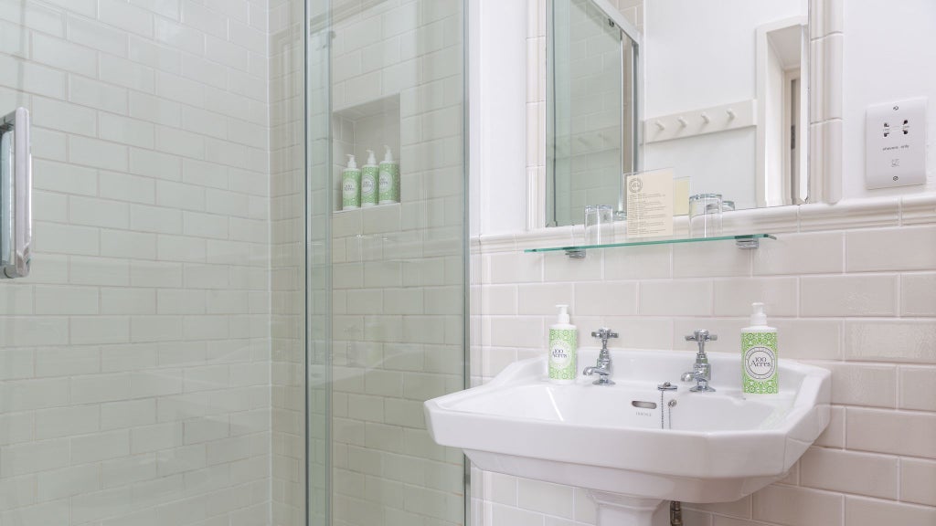 Luxurious modern bathroom with sleek glass shower, elegant neutral tiling, contemporary fixtures, and soft ambient lighting in a superior UK hotel room