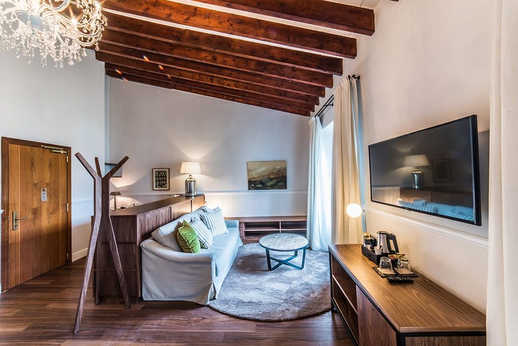 Elegant marble-floored luxury suite in Spain with plush white bed, modern minimalist decor, expansive windows overlooking scenic landscape at L'Avenida Sóller hotel