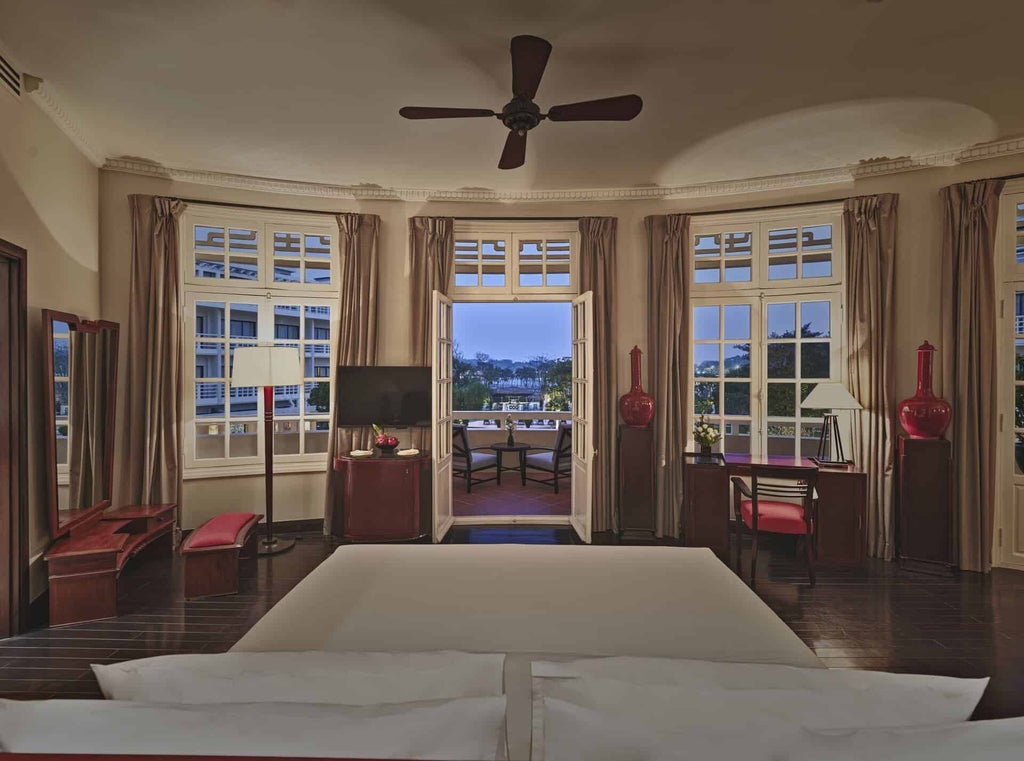 Elegant colonial-style suite with French-inspired decor, white walls, hardwood floors, and graceful four-poster bed at Azeraj in historic Hue, Vietnam