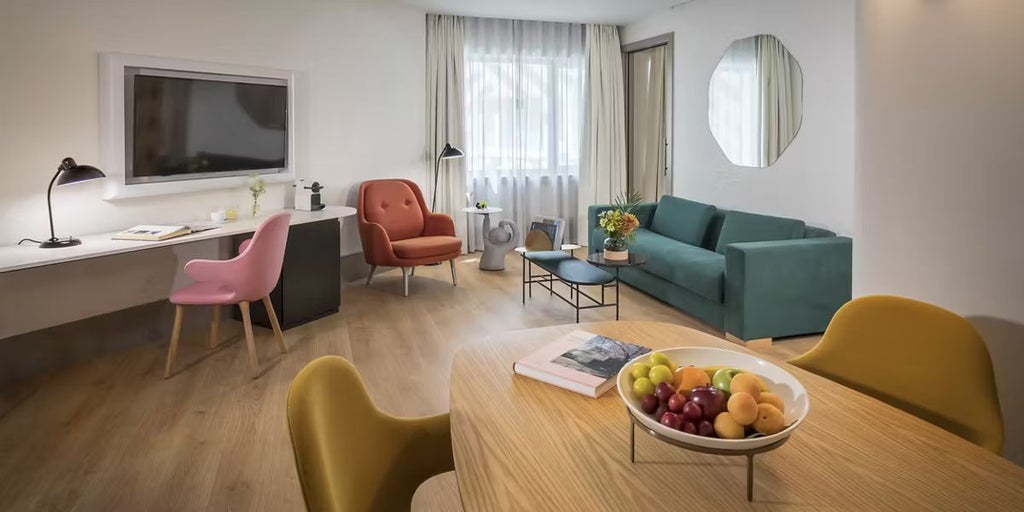 Modern luxury suite at Barceló Torre de Madrid with elegant neutral decor, floor-to-ceiling windows overlooking cityscape, contemporary furnishings, and sophisticated urban design.