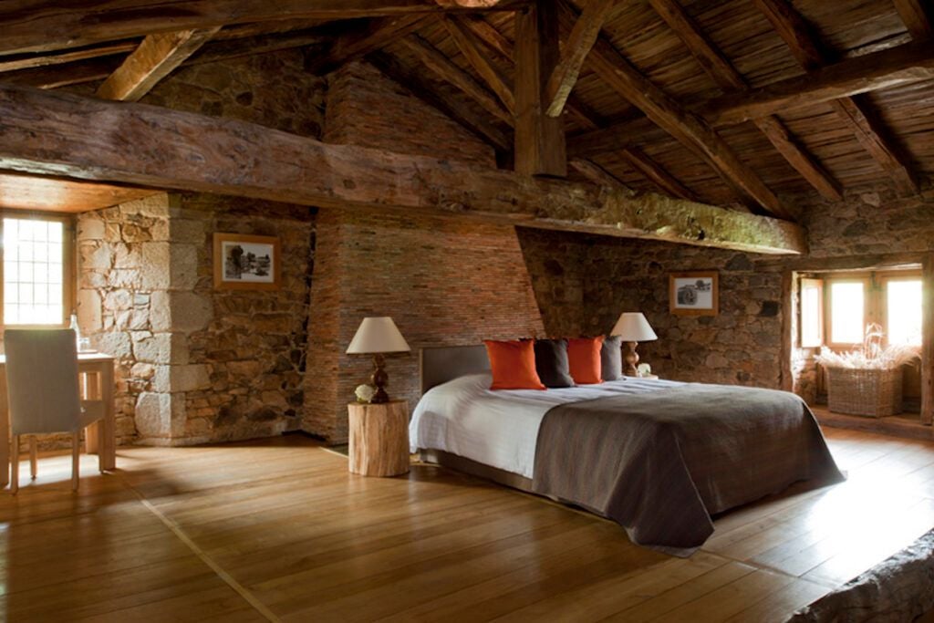 Luxurious French cottage bedroom with elegant wood furnishings, soft natural light, and panoramic countryside views at Domaine des Etangs resort