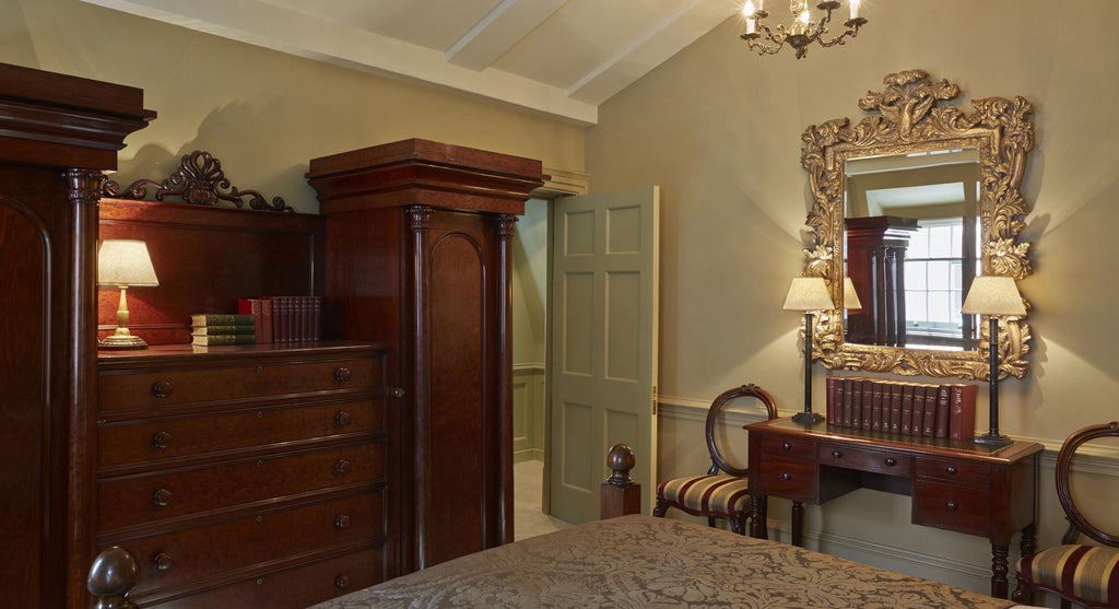 Elegant boutique hotel room with ornate four-poster bed, rich burgundy walls, vintage artwork, and opulent Georgian-inspired decor at Batty Langley's