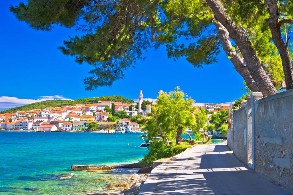 Historic stone pier and seaside promenade in Zadar, Croatia, with turquoise Adriatic waters and luxury yachts under clear blue skies