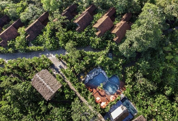 Luxurious boutique resort nestled in lush Costa Rican rainforest with modern bungalows featuring private terraces and volcanic views