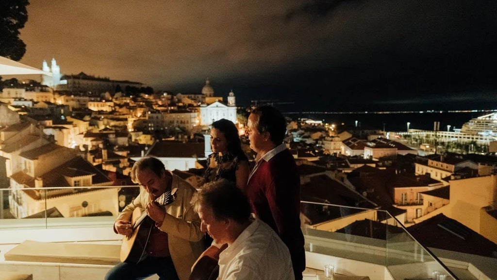 Luxurious boutique hotel terrace overlooking Lisbon's historic Alfama district, with traditional tiled rooftops and scenic cityscape at sunset