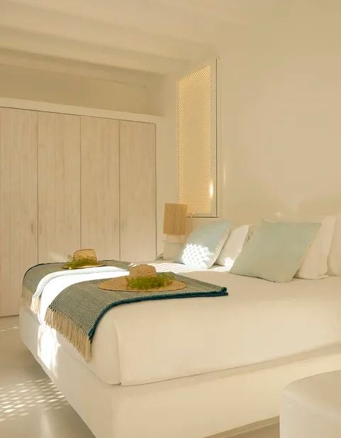 Luxurious white-walled bedroom with minimalist design, crisp linens, contemporary furnishings, and soft natural light in Portuguese villa retreat